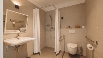 Un baño moderno con ducha, inodoro, lavabo y espejo.