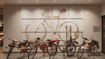 Une pièce dans laquelle on trouve un grand tableau abstrait accroché au mur, un vélo et une petite table sur laquelle sont disposés divers objets.
