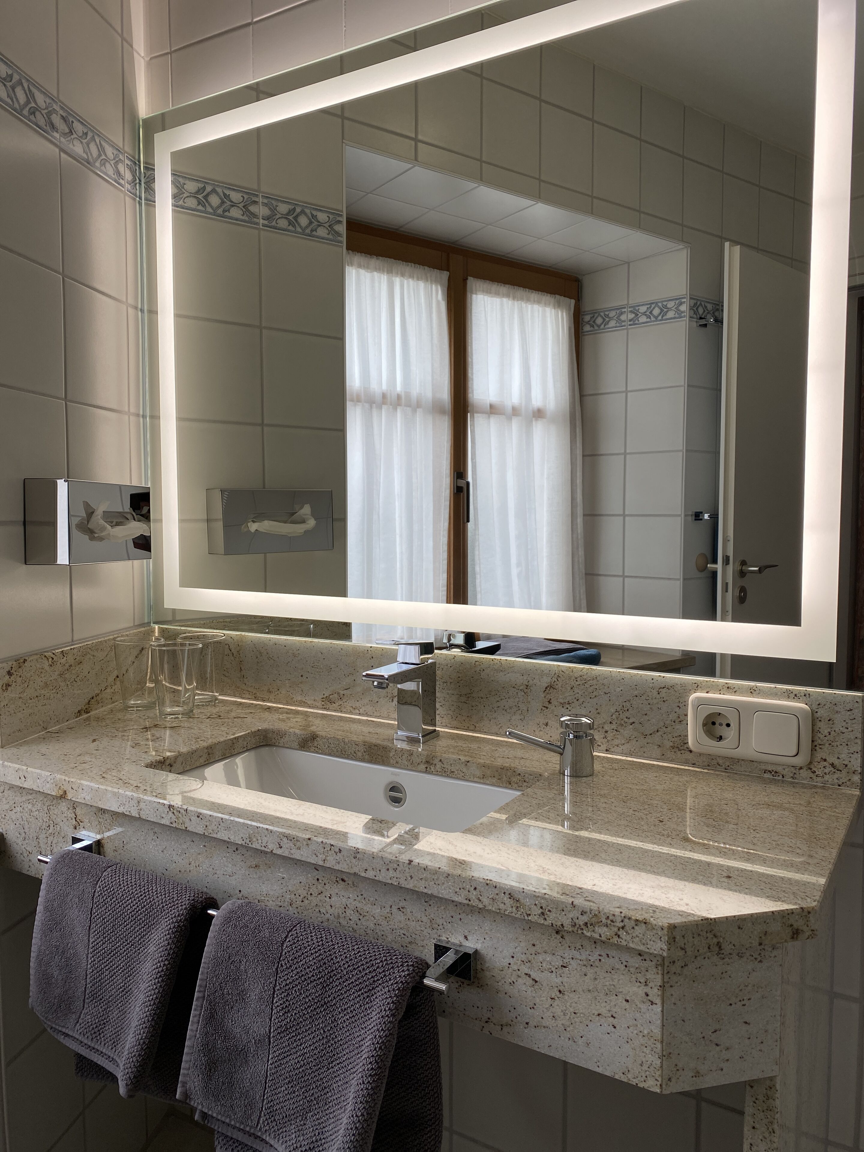 Une salle de bain avec un grand miroir, deux lavabos et un porte-serviettes avec deux serviettes.