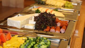 A buffet with various food items including cheese, sausages, and vegetables.