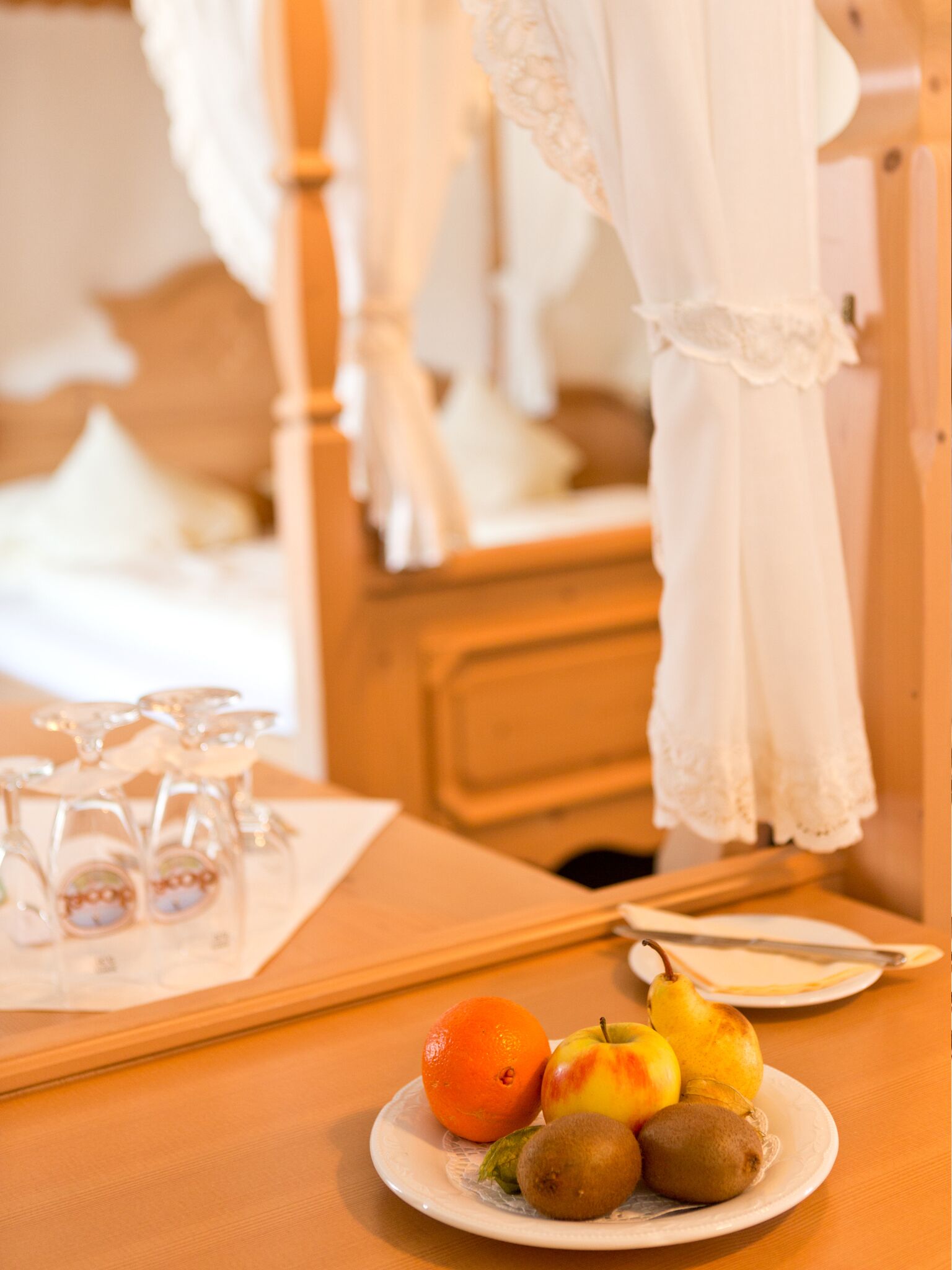 Un plato de fruta ordenado sobre una mesa de madera en una habitación de hotel, con una cama y una mesita de noche.