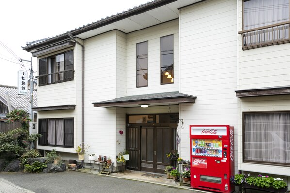 A two-story building with a Coca-Cola vending machine in front.