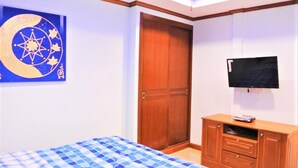 A bedroom with a bed, a wardrobe, a television, and a wall decoration.