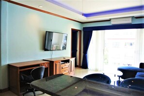 A hotel room with a desk, chair, and a television on the wall.