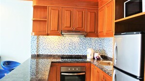 A kitchen with wooden cabinets, a tiled backsplash, a stainless steel oven, and a refrigerator.