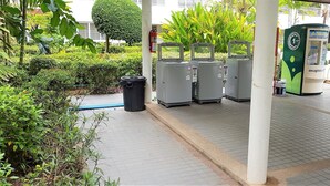 A covered outdoor area with a water fountain, trash bins, and a green vending machine.