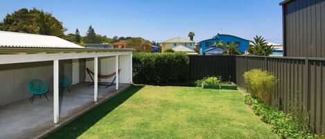 A backyard with a covered patio, a hammock, and a small garden area.