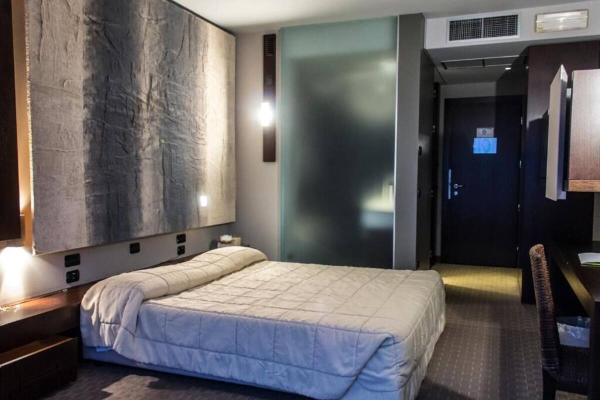 Una habitació d'hotel amb un llit gran, un escriptori i una cadira.