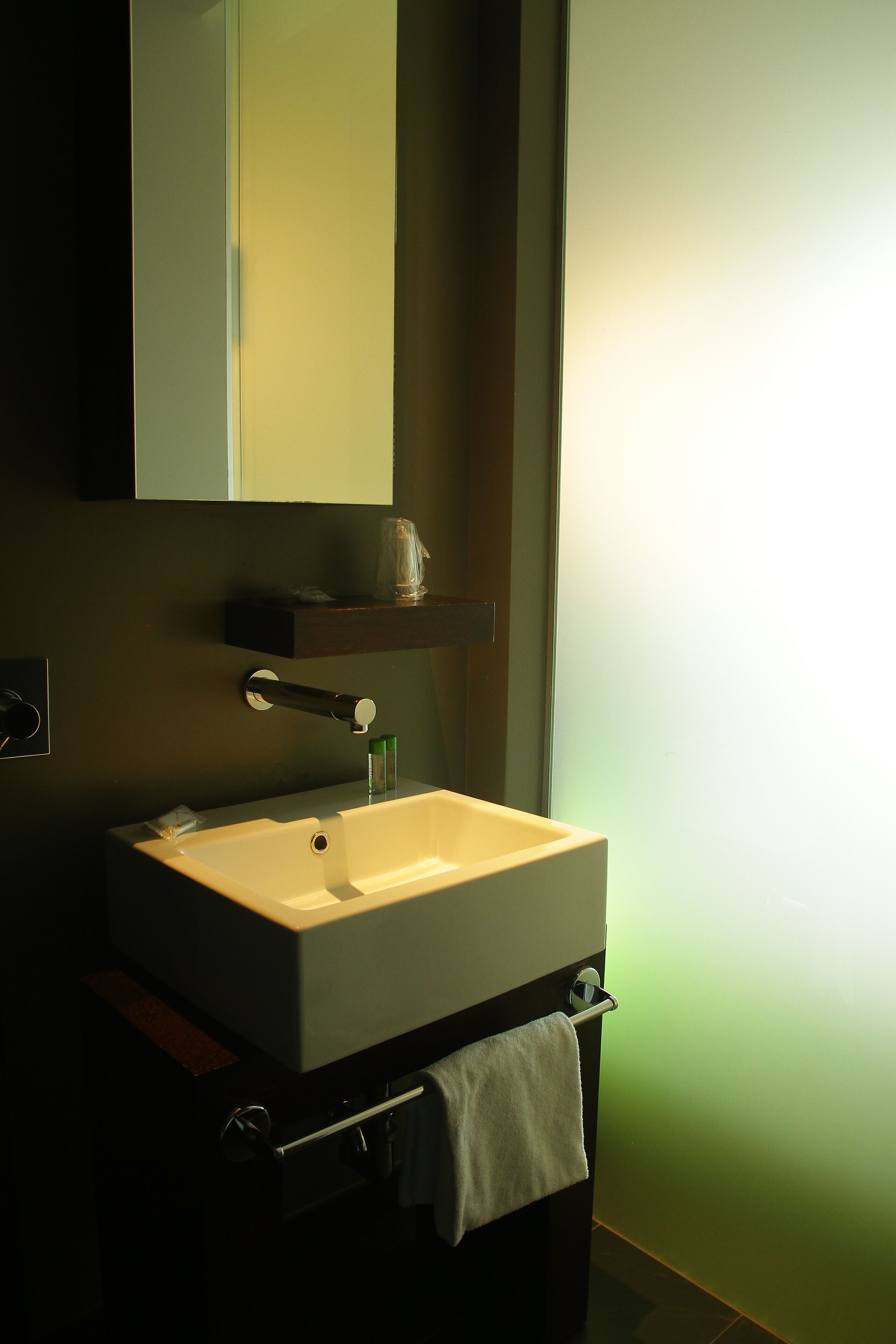Een badkamer met een witte wasbak, een spiegel erboven en een handdoek aan een rek.