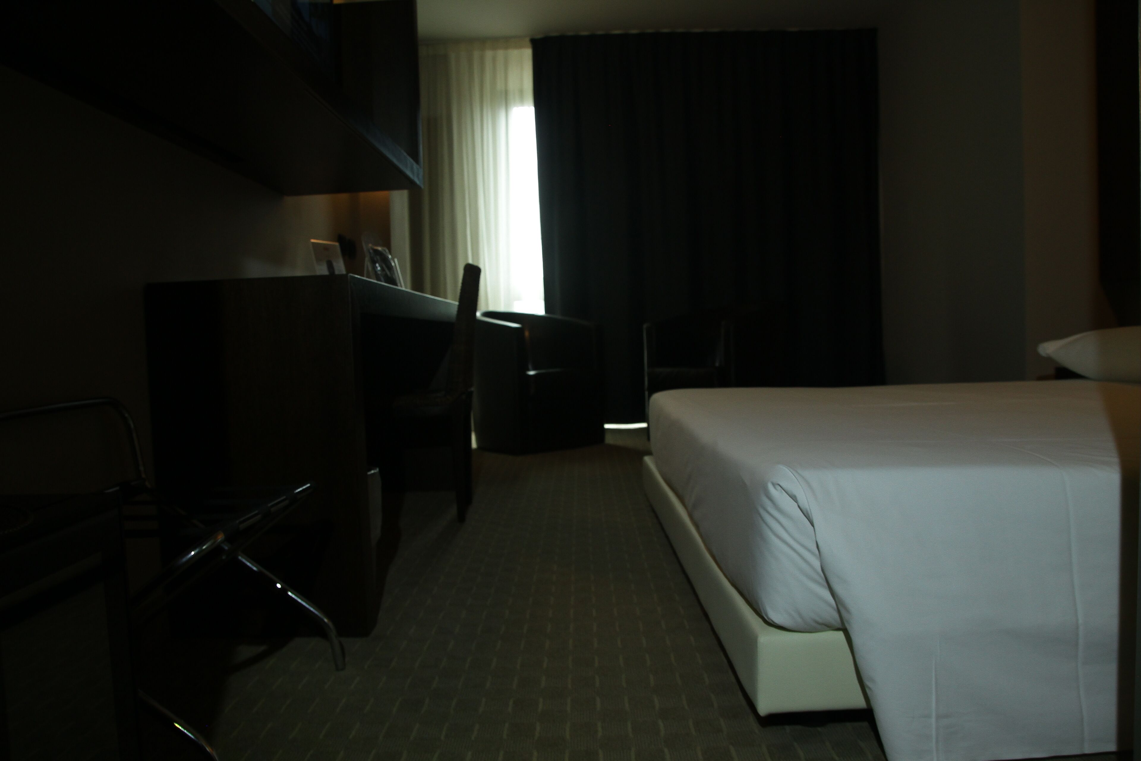 A hotel room with a bed, a desk, and a chair.