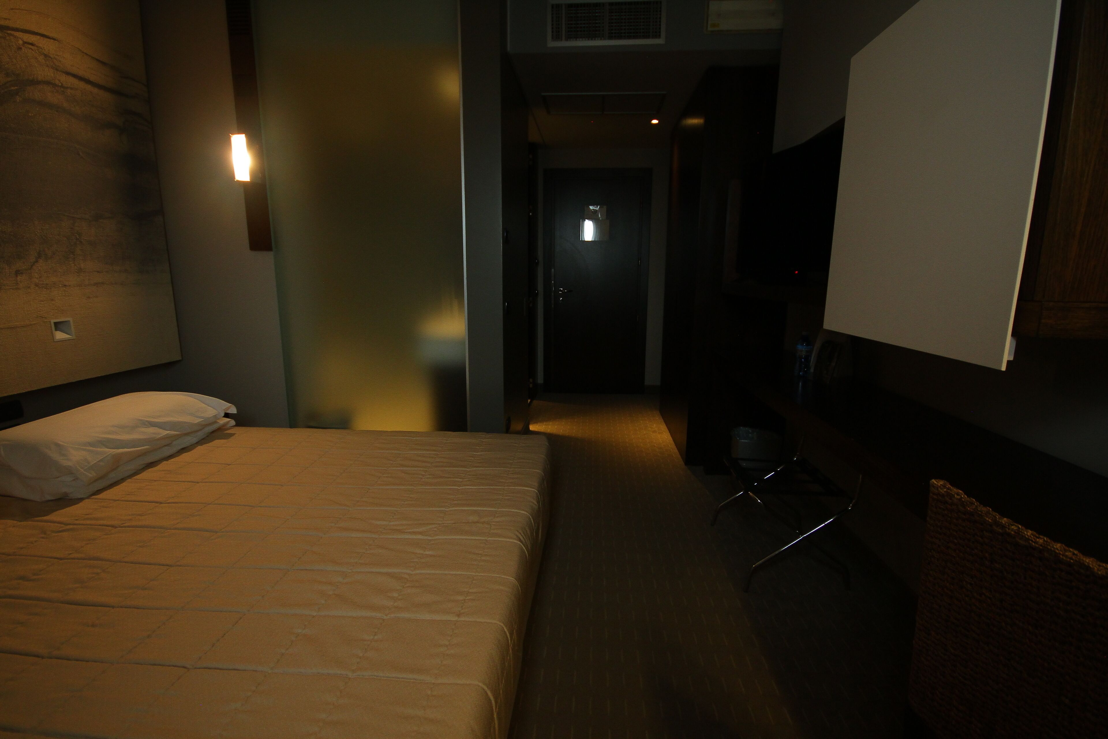 A hotel room with a bed, a chair, and a television.