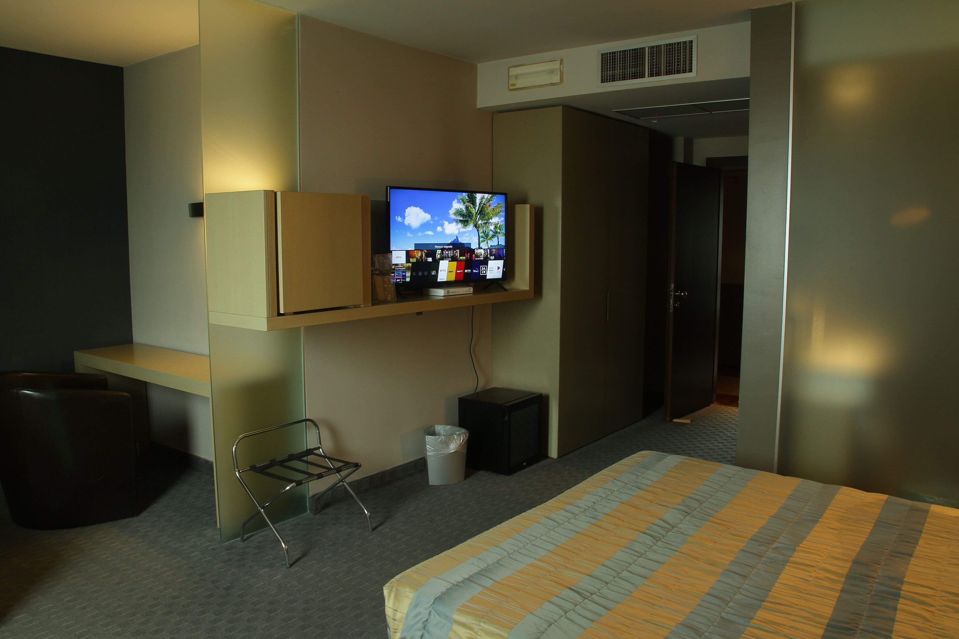 A hotel room with a bed, a desk, a television, and a trash bin.