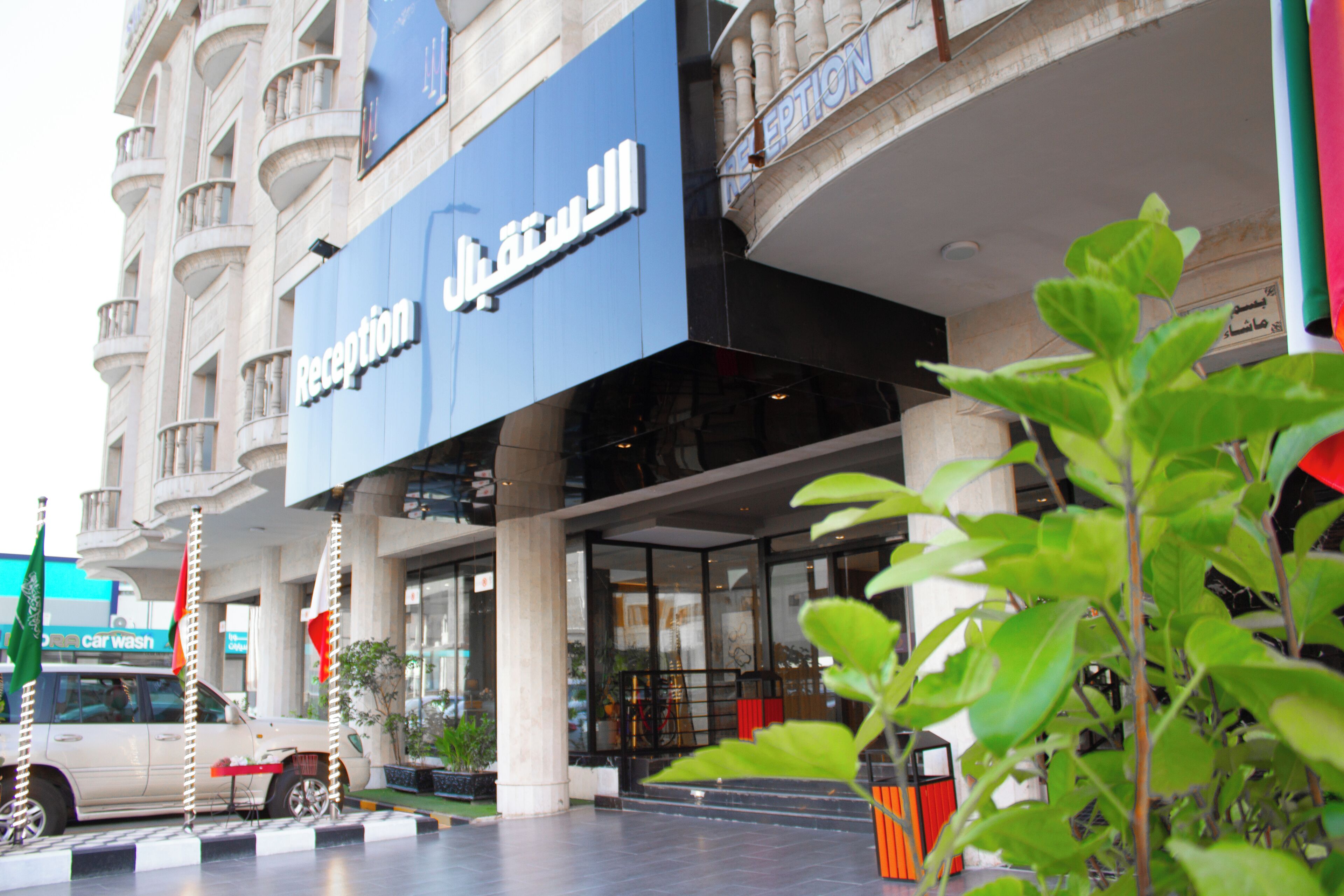 A hotel entrance with a reception area, columns, and a car wash sign in the background.