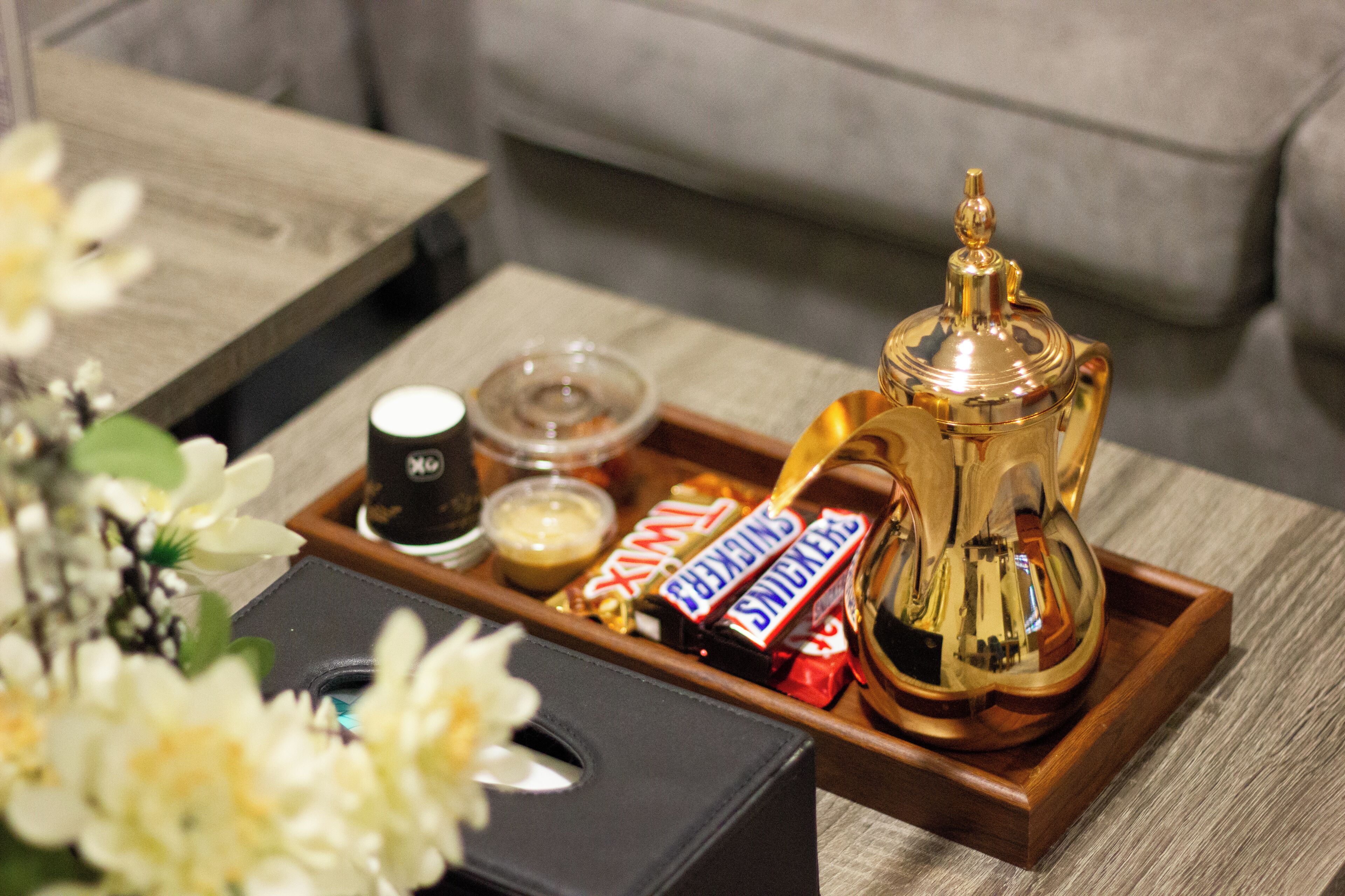 A tray with a coffee pot, a cup, and some snacks on a wooden table.