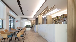 A modern interior with a long counter, seating area, and a visible kitchen in the background. - Hotel Toledo (Jesolo)