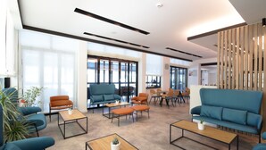 A modern lounge area with sofas, tables, and a wooden partition. - Hotel Toledo (Jesolo)
