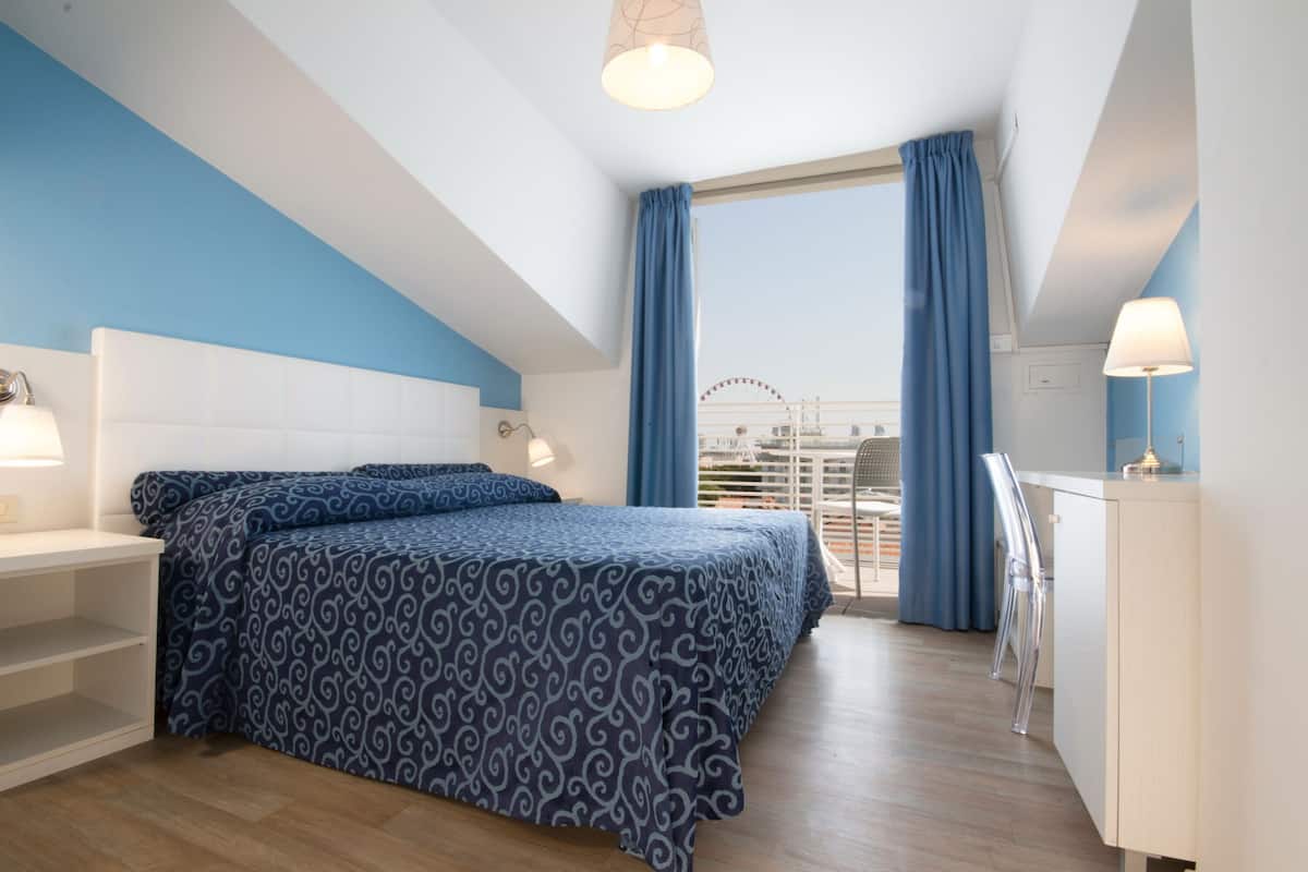 A bedroom with a bed, a desk, and a chair.