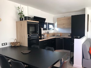 Una cucina moderna con elettrodomestici neri, un armadietto in legno e un'area pranzo con tavolo e sedie.