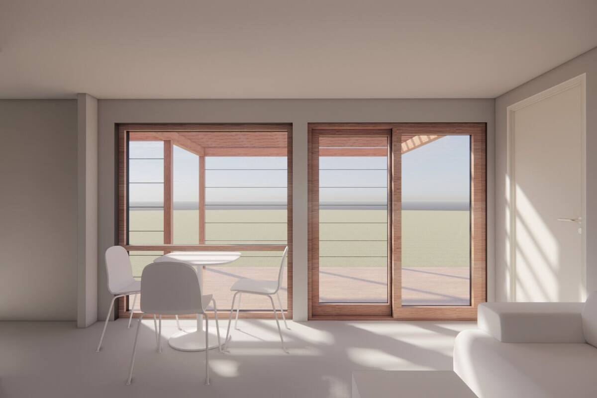 A modern room with a view of the beach, a white sofa, and a table with chairs.