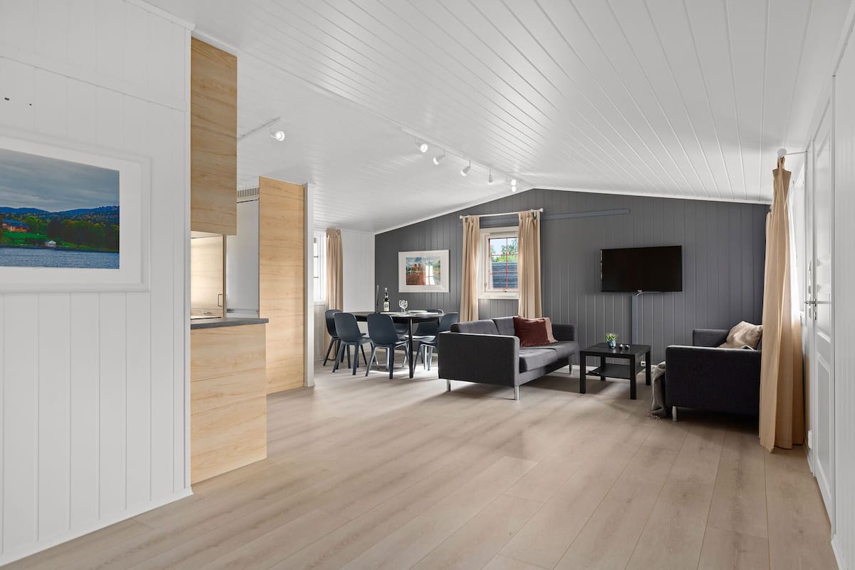 A spacious living area with a dining table, sofas, and a flat-screen TV.