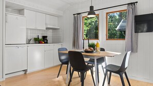 Een moderne keuken met witte kasten, een houten eettafel en zwarte stoelen.