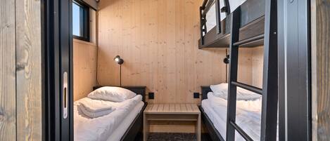 Habitación pequeña con literas, una mesita, una lámpara y una ventana.