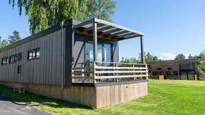 Een modern houten gebouw met een balkon, grote ramen en een helder uitzicht op de omgeving.