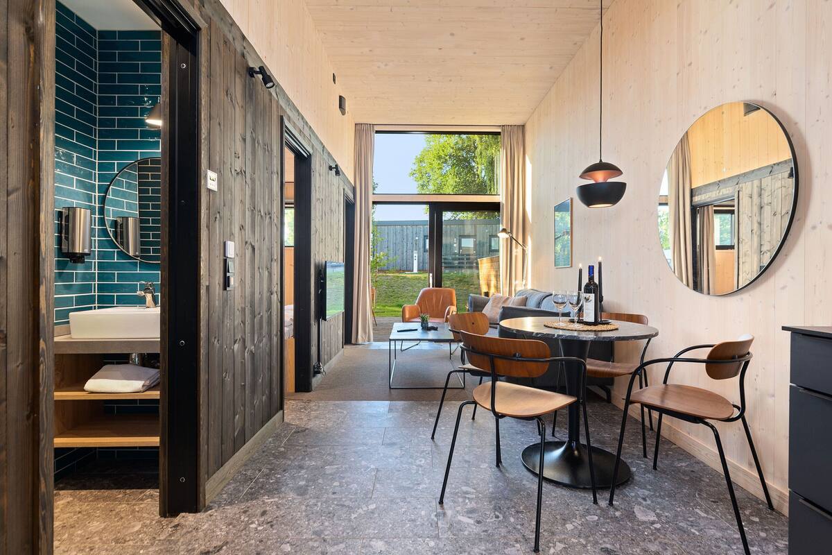 A modern interior with a bathroom, dining area, and large windows.