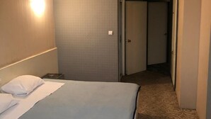 Une chambre d’hôtel avec un lit, une table de chevet, une lampe et une porte donnant sur une autre pièce.