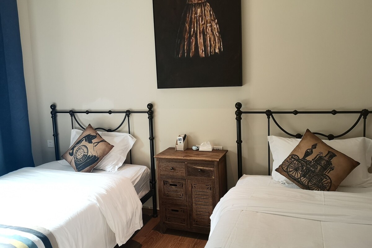 Ein Zimmer mit zwei Betten, jeweils mit Kissen und Nachttisch.