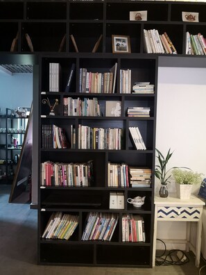 Ein Bücherregal voller Bücher, eine kleine Vase mit Blumen und ein Teekessel auf einem weißen Tisch.