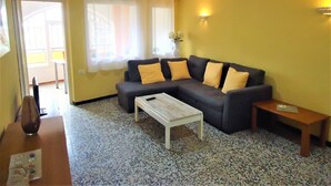 Una sala de estar con un sofá modular, una mesa de centro y una mesita auxiliar.