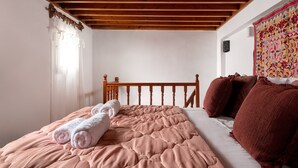 A bedroom with a wooden headboard, a pink quilted bedspread, and a brown blanket. - Acropolis Lindos Home (Rhodes)