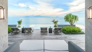 Une terrasse en bois avec des chaises longues et vue sur la mer.
