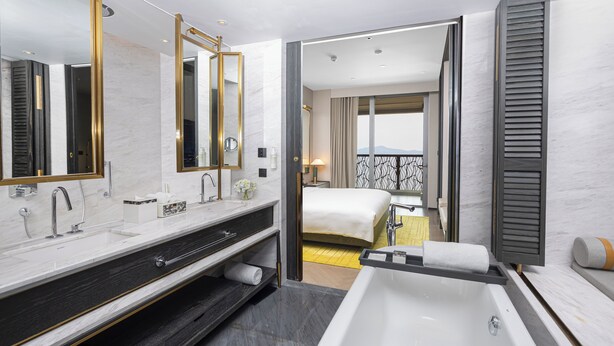 Une salle de bain d’hôtel moderne, dotée d’une grande baignoire, de deux vasques et d’un grand miroir.