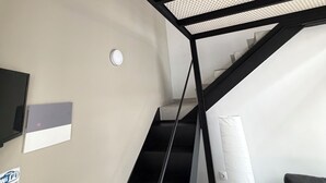 Una escalera con techo de diseño geométrico, barandal negro y pared blanca con señal de WiFi.