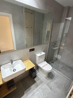 A modern bathroom with a sink, toilet, and glass shower enclosure. - athensdot (Athens)