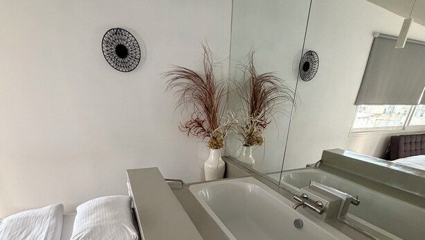 Un baño moderno con bañera, un espejo grande y dos apliques de pared.
