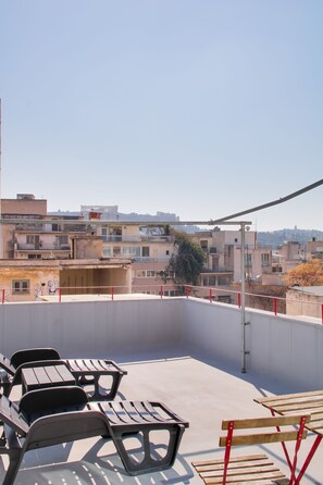 A rooftop terrace with outdoor seating and a view of surrounding buildings. - athensdot (Athens)