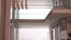Un interior amplio con un techo alto, una barandilla de cristal en el nivel superior y vistas despejadas al exterior.