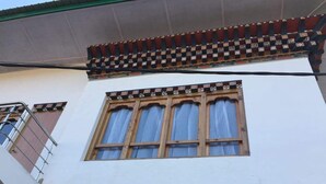 Ein Gebäude mit weißer Fassade, einem Balkon mit Metallgeländern und einem Fenster mit Holzrahmen und Vorhängen.
