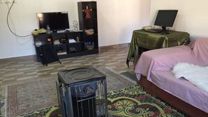 Ein Zimmer mit einem Bett, einem Heizgerät, einem Fernseher und einem Regal mit verschiedenen Gegenständen.