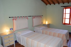 Un dormitorio con dos camas, una mesita de noche con lámpara y una ventana con vistas.