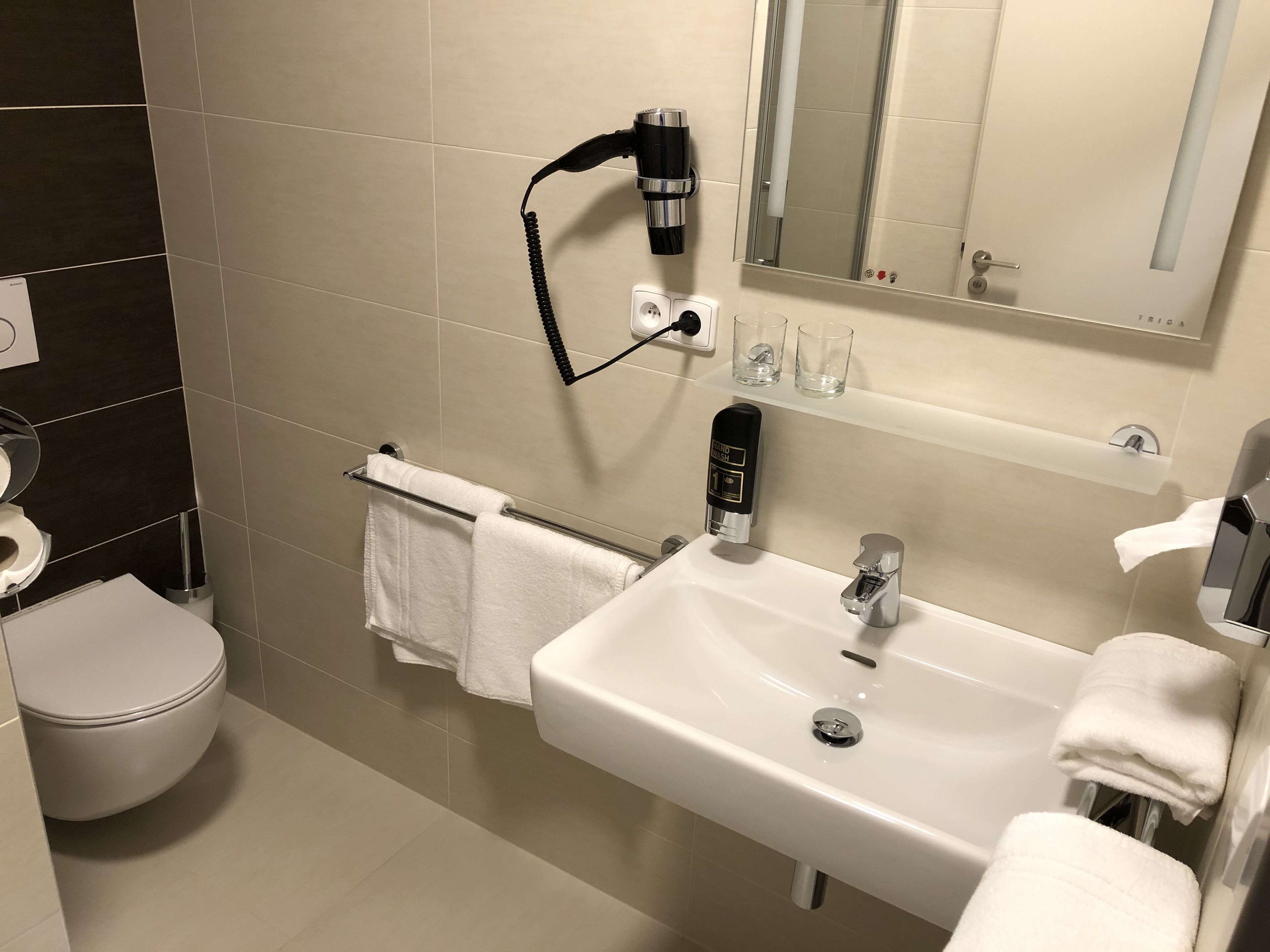 A modern bathroom with a toilet, sink, and towel rack.