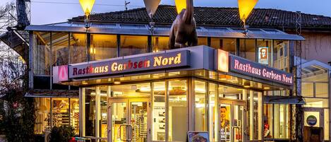 Un restaurante llamado "Resthaus Garbsen Nord" con una gran estatua de un ave en el techo, un letrero y suelo adoquinado.