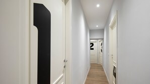 A hallway with white walls, wooden flooring, and doors numbered 1 and 2. - Affittacamere I Canneggiatori (Abbadia San Salvatore)