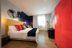 Un dormitorio con cama, un armario rojo y un ventilador de pared.