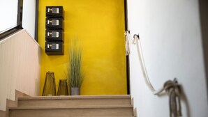 A staircase with beige steps leading to a yellow wall with a security keypad and a potted plant. - Affittacamere I Canneggiatori (Abbadia San Salvatore)