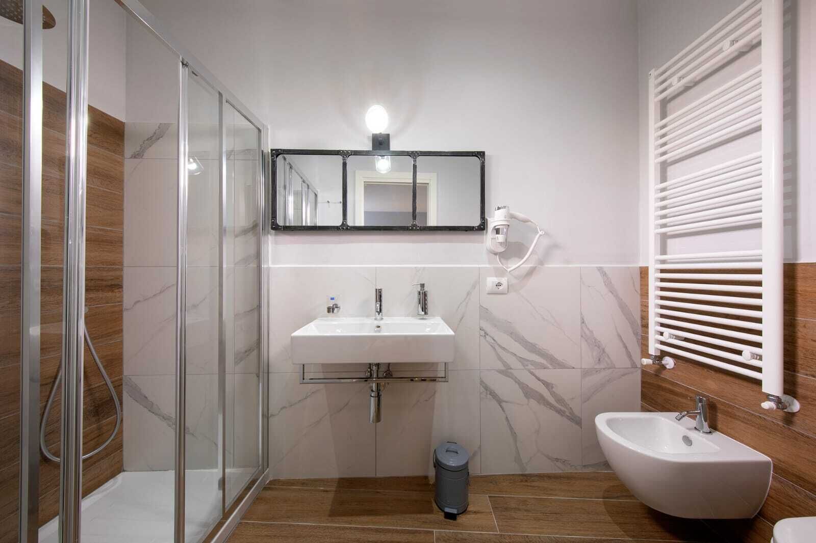 Une salle de bain moderne avec une douche à parois de verre, un lavabo blanc, un bidet et un porte-serviettes.