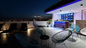 Un bar en la azotea con sillones de relax y una zona de bar.